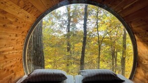 A circular wooden room with a bed and two pillows. - Family & Pet Friendly Treehouse with Amazing Views (Wildwood)