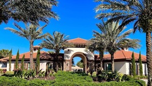 A building with a central arched entrance, surrounded by palm trees and well-maintained landscaping.