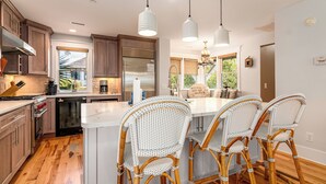 Una cocina moderna con armarios de madera, un refrigerador de acero inoxidable y una isla grande con sillas de mimbre.