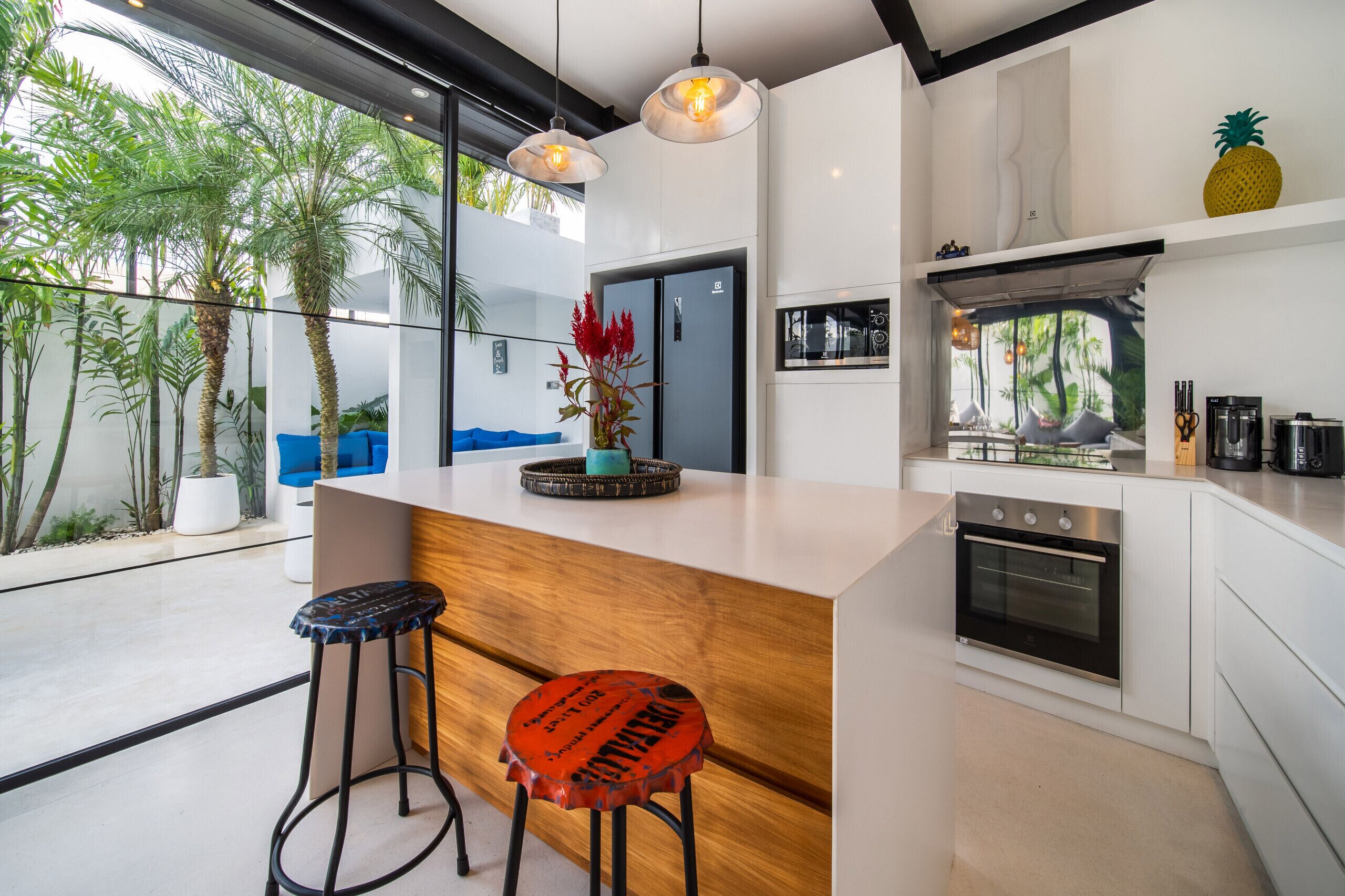 A modern kitchen with a central island, bar stools, and a built-in oven.