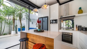 A modern kitchen with a central island, bar stools, and a built-in oven. - Private Pool • Daily Housekeeping • Walk to Canggu (Canggu)