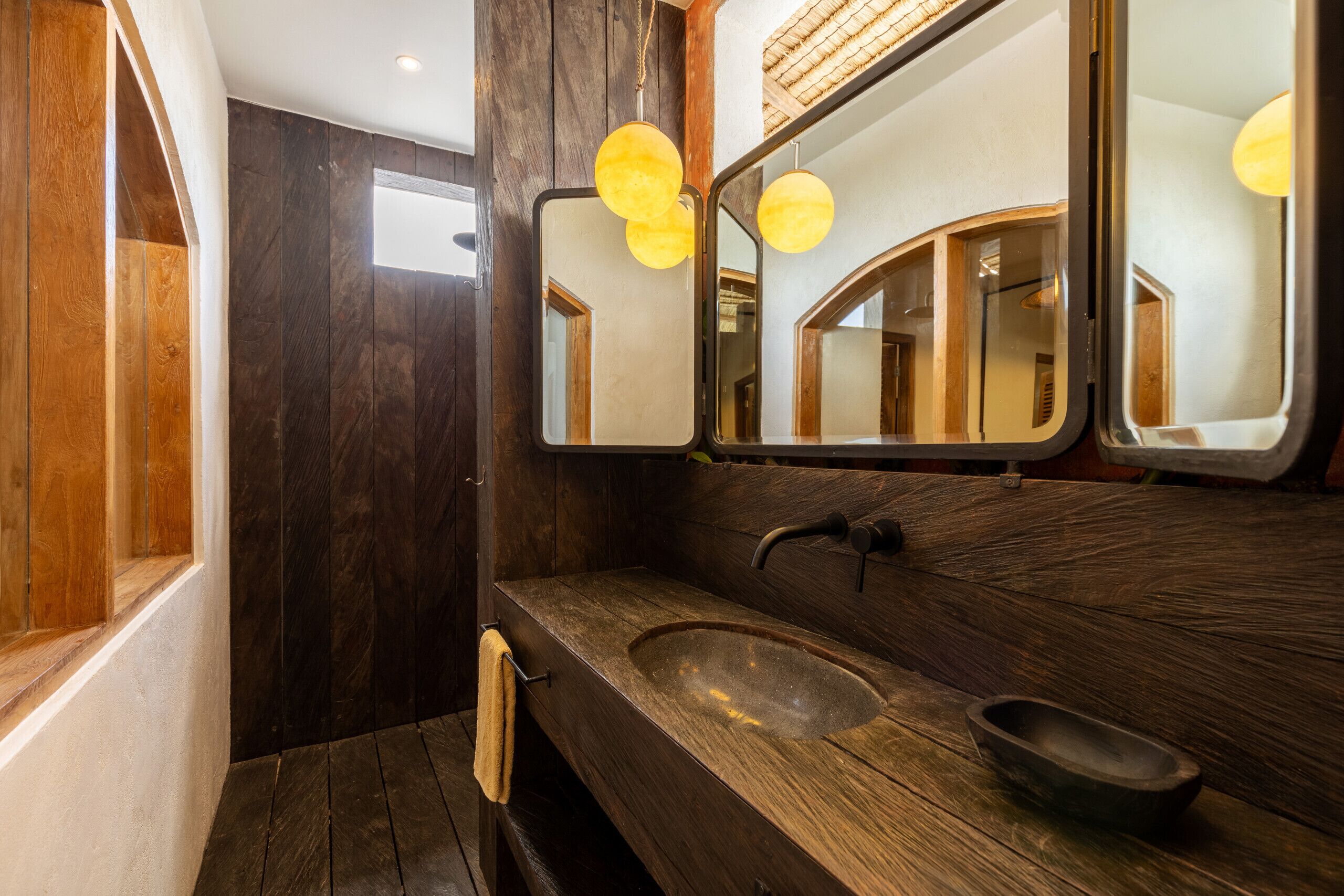 Ein modernes Badezimmer mit einem Holzlagerflächenschrank, einem großen Spiegel und einem runden Waschbecken.