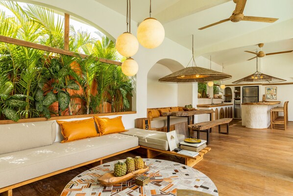 A spacious living area with a sofa, wooden coffee table, and a dining area with a bar.