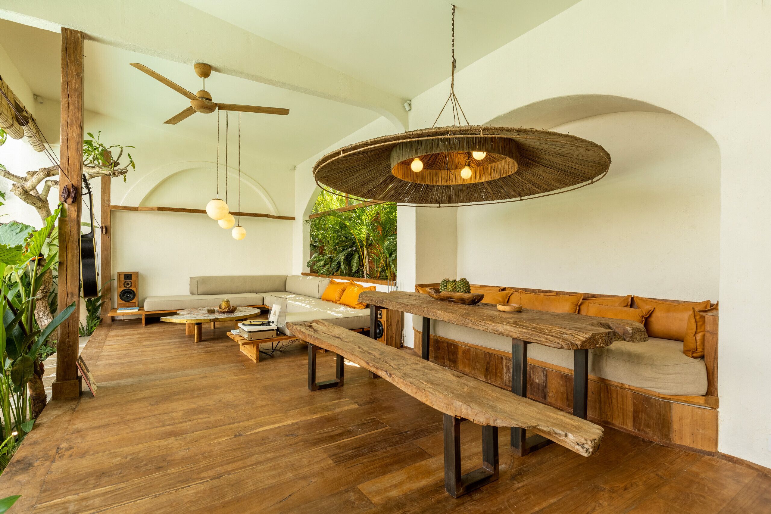 A spacious living area with a wooden bench, a sofa, and a ceiling fan.