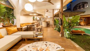 A spacious indoor area with a pool, wooden furniture, and large plants. - Tropical Garden | Three Bedrooms | Walk to Cafés (Kerobokan)