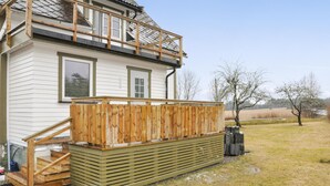 Ein zweistöckiges Haus mit einer Holzterrasse und einer kleinen Treppe zu einem Balkon.