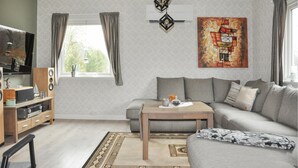 Ein Wohnzimmer mit Sofa, Couchtisch, Fernseher, Lautsprechern und Kunstwerken.