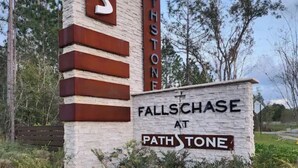 A sign for 'Fallschase at Pathstone' with a stone and metal design, surrounded by greenery. - Casa De los Pensacola (Pensacola)