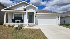 A single-story house with a front porch, a garage, and a covered driveway. - Casa De los Pensacola (Pensacola)