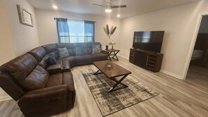 A modern living room with a sectional sofa, a coffee table, and a flat-screen TV. - Casa De los Pensacola (Pensacola)