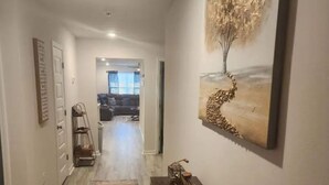 A hallway with a wooden bench, a rug, and a painting of a tree. - Casa De los Pensacola (Pensacola)