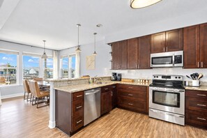A modern kitchen with dark wood cabinets, stainless steel appliances, and a large island with seating. - Canal | Hot Tub | Large Deck | Private Dock | Pets (Galveston)