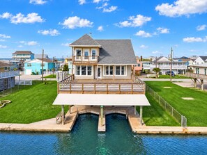 A two-story house with a balcony, a pool, and a view of the ocean. - Canal | Hot Tub | Large Deck | Private Dock | Pets (Galveston)