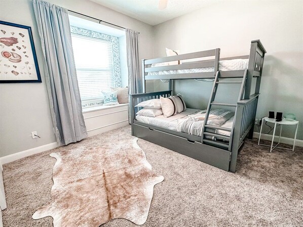 A bunk bed room with a cowhide rug, a framed picture, and a small table with speakers.
