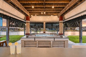 A hot tub area with a view of a body of water, wooden beams, and a concrete structure. - Canal | Hot Tub | Large Deck | Private Dock | Pets (Galveston)