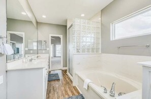 Une salle de bain moderne dotée d’une grande baignoire, de deux lavabos et d’une cabine de douche en verre.