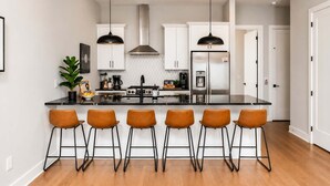 A modern kitchen with a central island, bar stools, pendant lighting, and stainless steel appliances. - Nashville Getaway • Hot Tub & Sleeps 12 (Nashville)