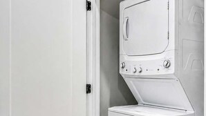 A laundry room with a white washing machine and dryer, a white door, and a tiled floor. - Nashville Getaway • Hot Tub & Sleeps 12 (Nashville)