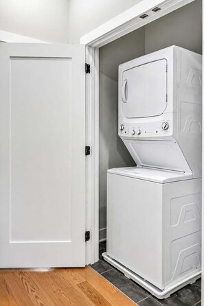A laundry room with a white washing machine and dryer, a white door, and a tiled floor.
