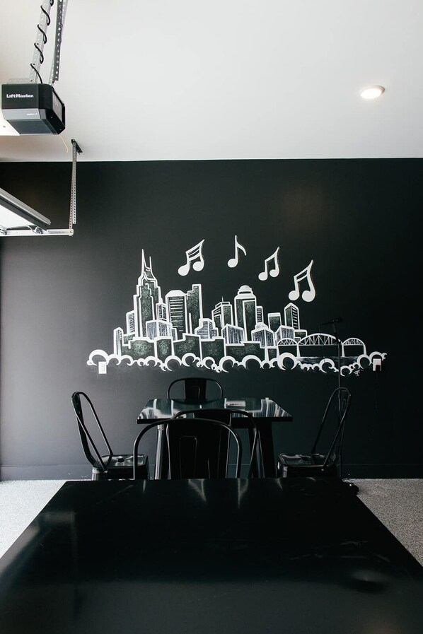 A conference room with a black table and chairs, a city skyline mural with musical notes, and a projector mounted on the ceiling.
