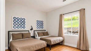 A bedroom with two beds, a window with curtains, and artwork on the wall. - Nashville Getaway • Hot Tub & Sleeps 12 (Nashville)