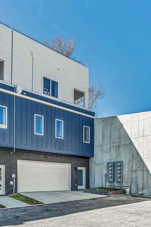 A modern two-story building with a garage, a concrete ramp, and a clear blue sky. - Nashville Retreat • Rooftop Skyline & 12 Guests (Nashville)