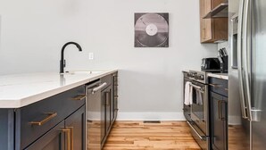 A modern kitchen with a central island, stainless steel appliances, and a wooden floor. - Nashville Retreat • Rooftop Skyline & 12 Guests (Nashville)