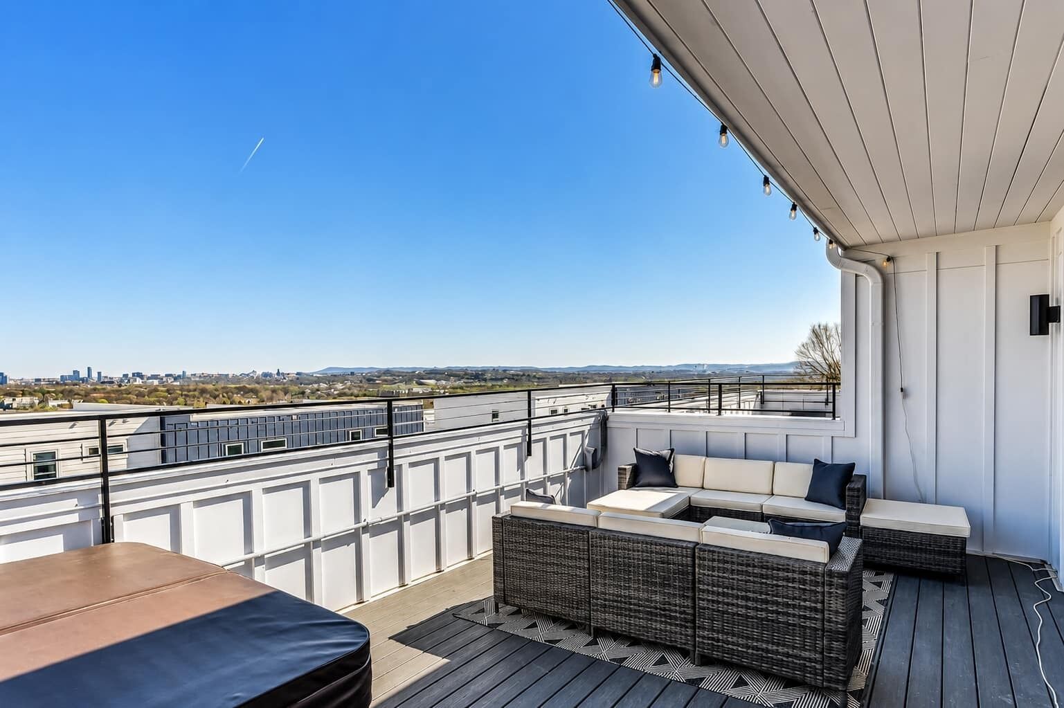 A rooftop terrace with a seating area, a table, and a view of the cityscape.