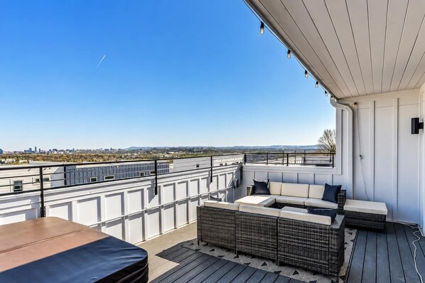 A rooftop terrace with a seating area, a table, and a view of the cityscape.