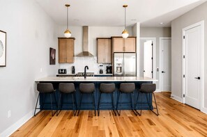 A modern kitchen with a central island, bar stools, and stainless steel appliances.