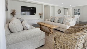 Un salon moderne avec un ensemble de canapés, une table basse en bois et un téléviseur fixé au mur.