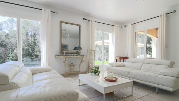 A spacious living room with a white sofa set, a coffee table, and a large window with curtains. - Peaceful Villa with Infinity Pool, 10' from Center (Antibes)