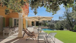 An outdoor patio with a pool, lounge chairs, and a dining area with a table and chairs. - Peaceful Villa with Infinity Pool, 10' from Center (Antibes)