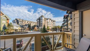 Un balcone con vista su un edificio a più piani, dotato anch'esso di balconi, e una strada sottostante.