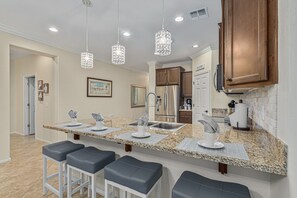 A modern kitchen with granite countertops, stainless steel appliances, and pendant lighting.