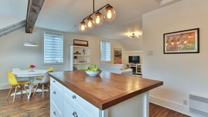 A modern kitchen with a wooden island, white cabinetry, and a dining area with yellow chairs. - Charming 2 bedroom rental unit in Knowlton village (Knowlton)