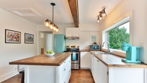 A modern kitchen with white cabinets, a wooden countertop, and a window providing a view of greenery outside. - Charming 2 bedroom rental unit in Knowlton village (Knowlton)
