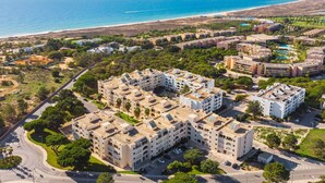 Luchtbeeld van een kusthotelcomplex met meerdere gebouwen, wegen en een strand op de achtergrond.