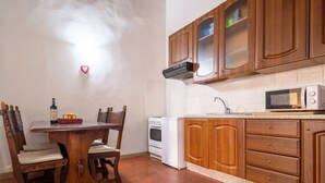 A kitchen with wooden cabinets, a white stove, a microwave, and a dining table with chairs. - Palazzo Vecchio Place by Mmega (Firenze)