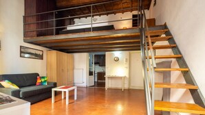 A loft-style room with a wooden staircase, a sofa, a small table, and a kitchen in the background. - Palazzo Vecchio Place by Mmega (Firenze)