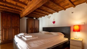 A bedroom with a wooden ceiling, a bed with white linens, a bedside lamp, and wooden cabinets. - Palazzo Vecchio Place by Mmega (Firenze)