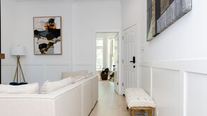 A hallway with a white sofa, a bench, and a floor lamp.