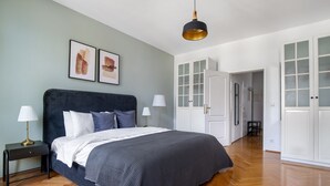 Un dormitorio con cama, mesitas de noche, lámpara colgante y un armario.