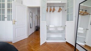 Un closet amplio con puertas abiertas, perchas de madera y un espejo.
