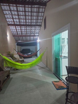 A hallway with a hammock, a car, and a sliding glass door leading to a balcony.