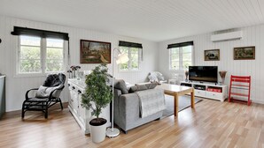 A spacious living room with a sofa, a chair, a TV, and a dining table.