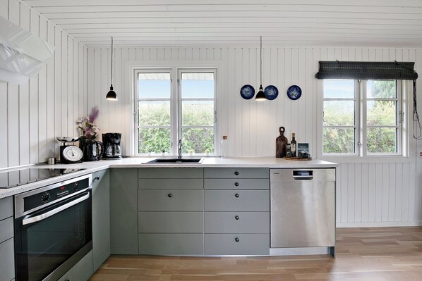 A kitchen with a built-in oven, a sink, and a large island with drawers.