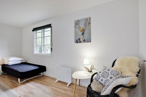 A room with a bed, a radiator, a chair, a table with a lamp, and a window. - Lovely cottage for family and friends (Kirke Hyllinge)