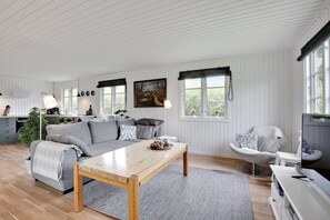A modern living room with a sofa, coffee table, and a television. - Lovely cottage for family and friends (Kirke Hyllinge)