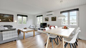 A modern living room with a sofa, coffee table, dining table, and chairs.